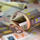 Half rolled fifty euro banknote on fifty euros banknotes background. Close up shot, Selective focus.