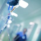 Intravenous drip with blue liquid ready to use on the background of walking around medical doctor, concept of mercy killing
