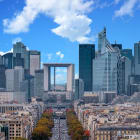 La Defense Financial District Paris France in autumn. Traffic on Champs-Elysees with orange and yellow trees aside. Modern vs. Old architecture. Blue sky with clouds.