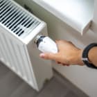 A woman’s hand turns the battery heating knob. Heating in an apartment, at home. Heating prices.