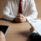 HR manager woman reading resume and writing data on tablet during job interview with male candidate