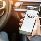 Homme tenant au volant son téléphone avec l'application Uber ouverte