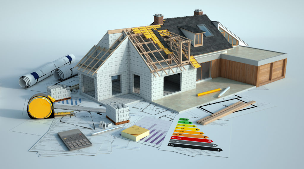 Maquette de maison avec une partie en construction posée sur des documents et matériel de dessin