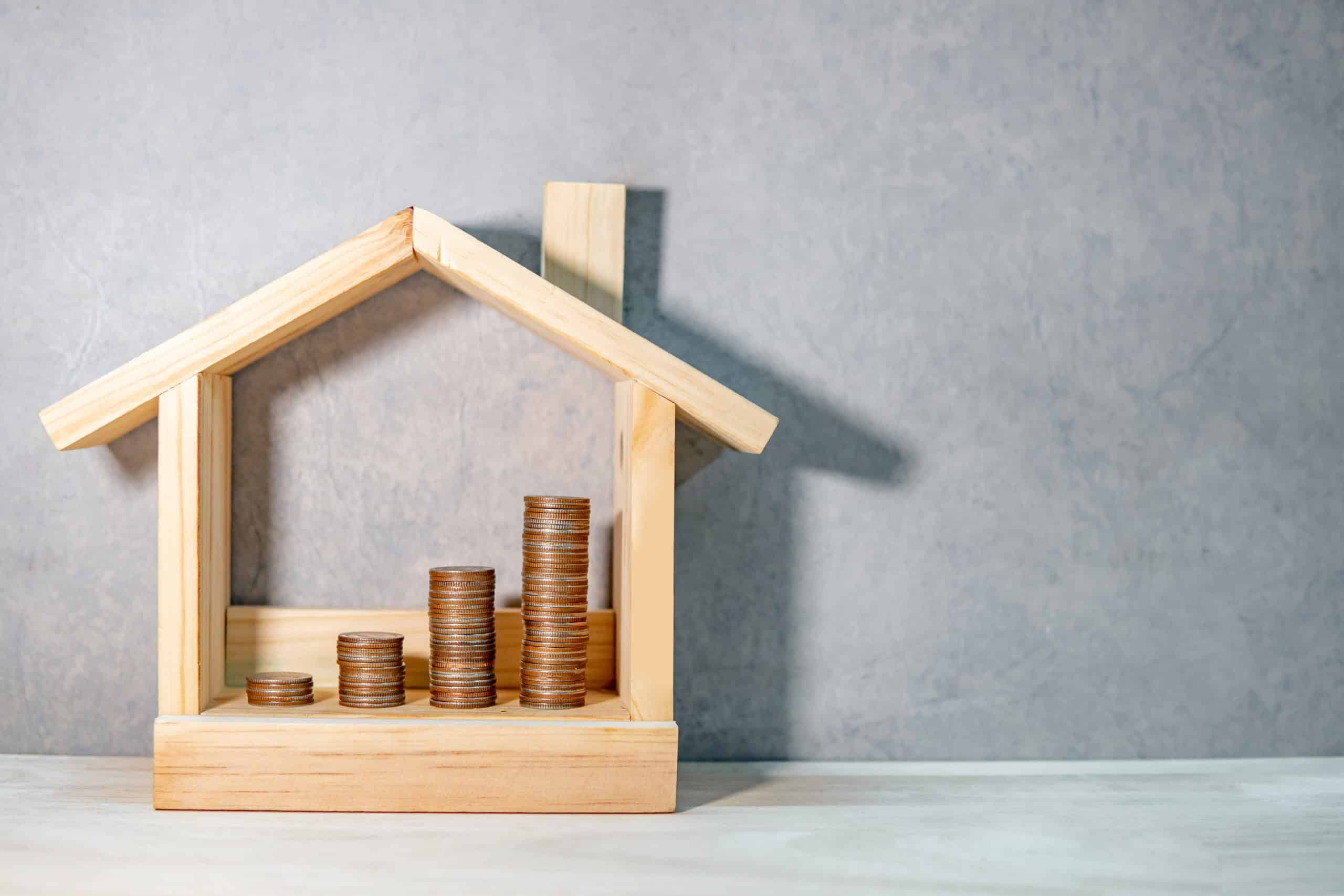 Construction en bois représentant une maison avec des pièces de monnaie à l'intérieur