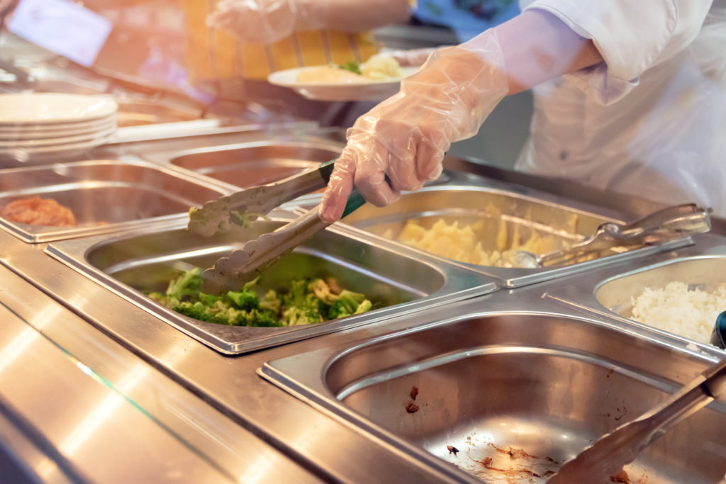 Personne servant une assiette dans une cantine