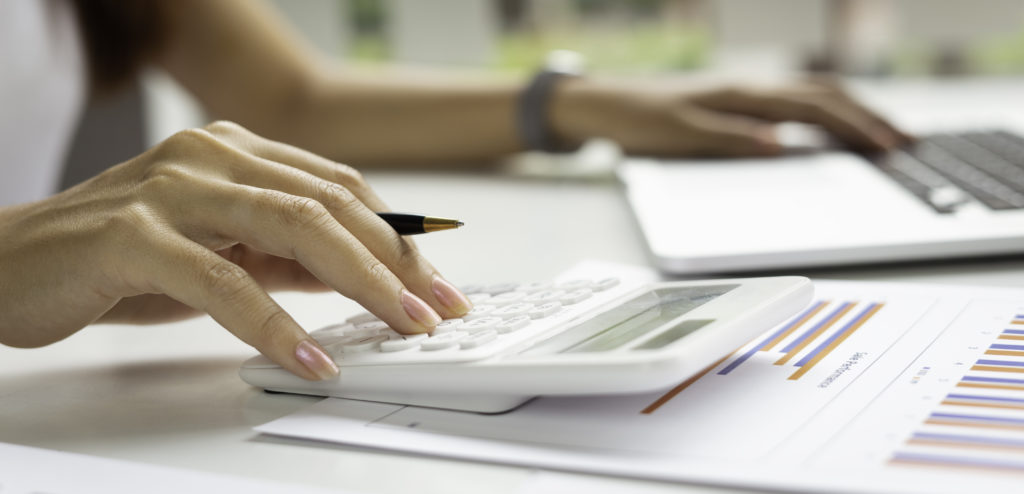 Mains de femme tapant sur une calculatrice et un ordinateur portable