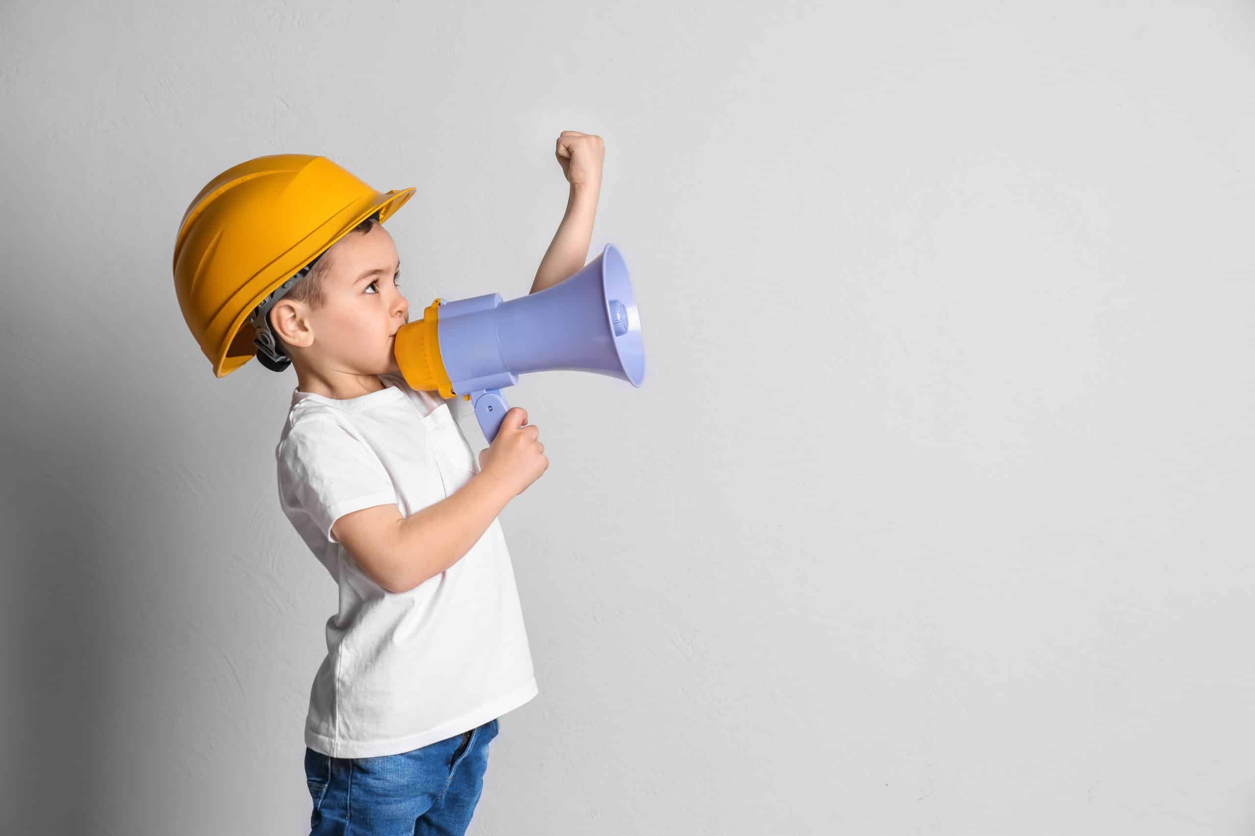 Enfant avec un casque de chantier et un mégaphone, le poing levé