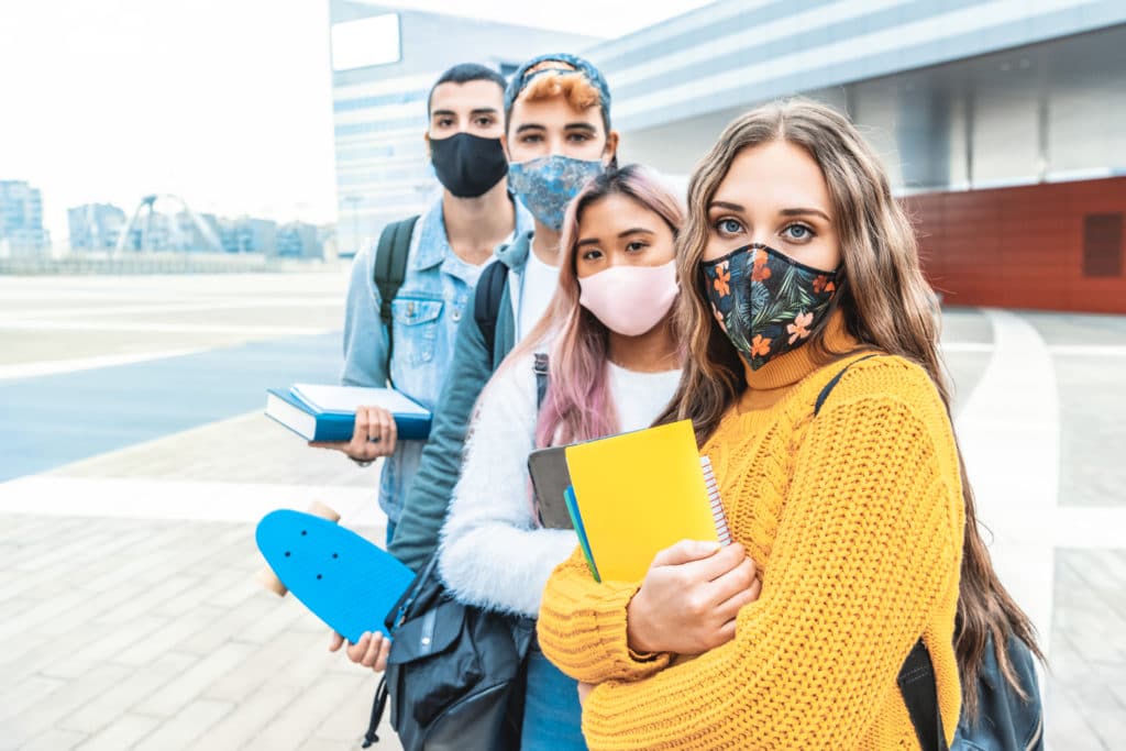 Portrait de quatre étudiants portant des masques devant un bâtiment