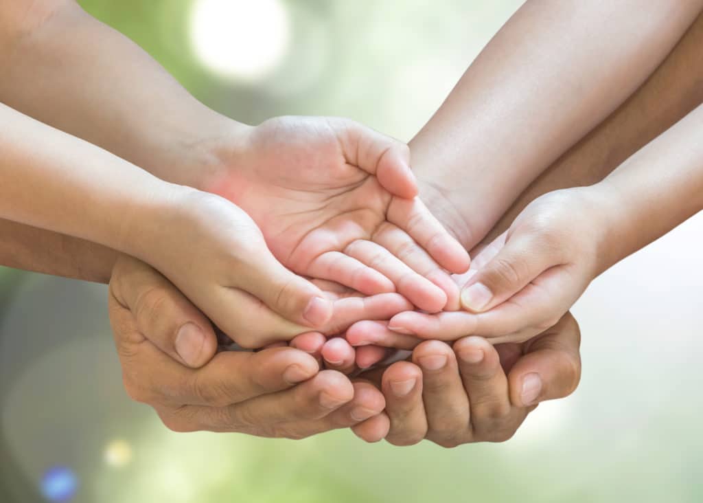 Mains d'enfant au dessus des mains de ses parents, paume vers le ciel