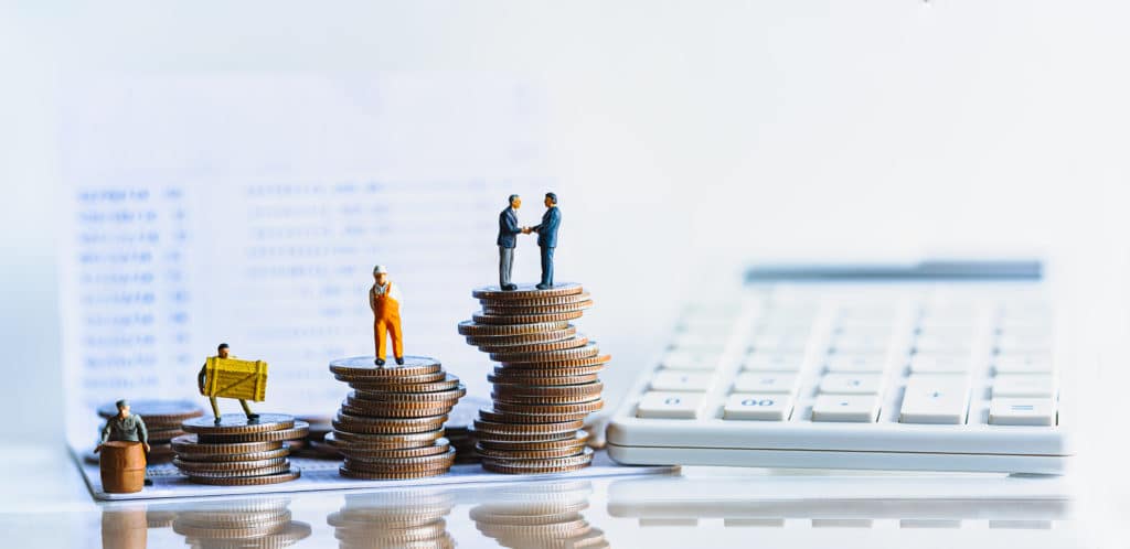 Figurines de personnages sur des piles de pièces. Près d'un clavier d'ordinateur