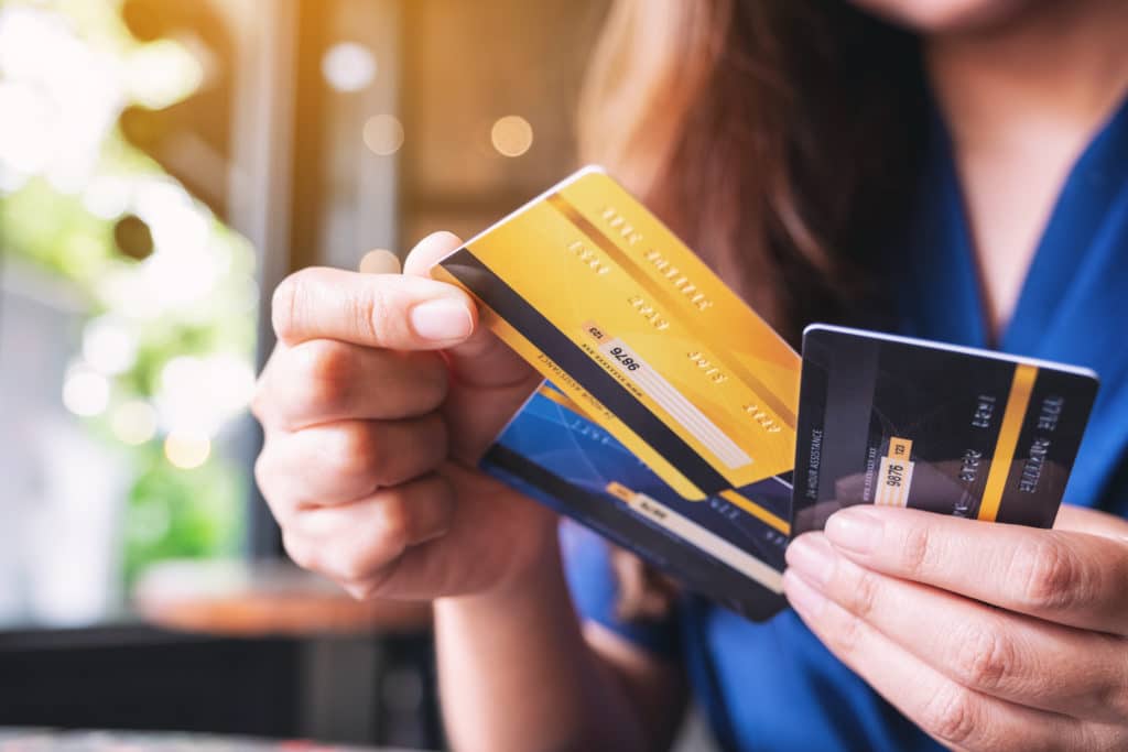 Une main tend une carte de paiement parmi 3 cartes e paiement