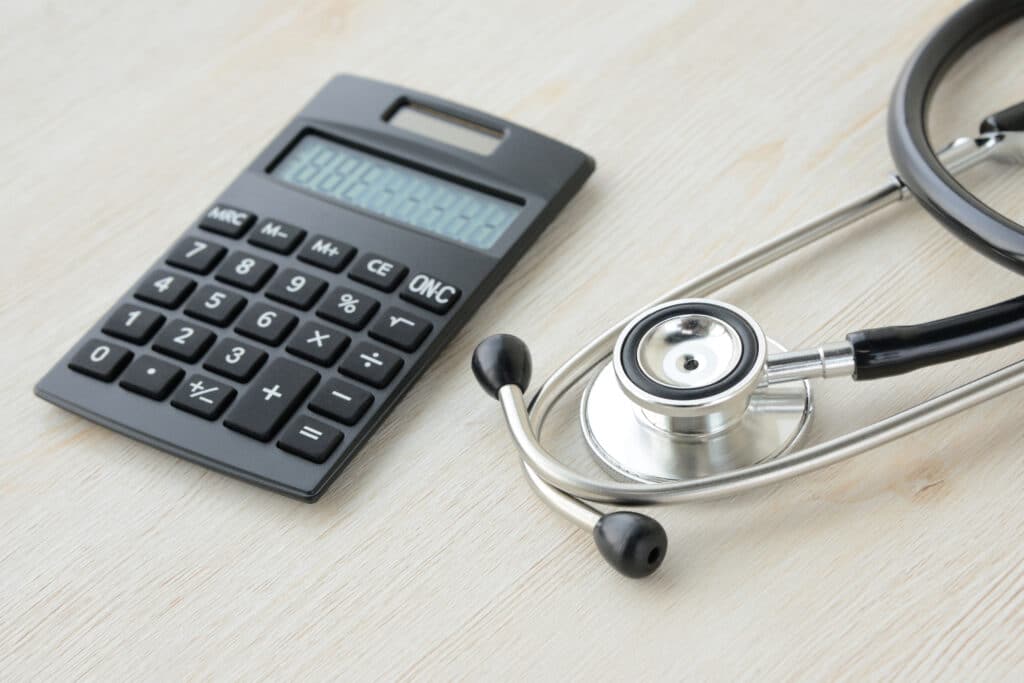 Calculatrice et stéthoscope posés sur une table, image conceptuelle dela responsabilité médicale